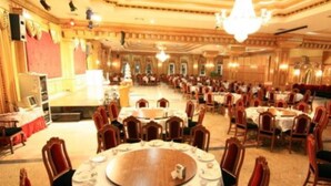 A banquet hall with round tables set for dining, a stage, and a seating area with chairs. - 13 Coins Ngamwongwan Hotel (Nonthaburi)