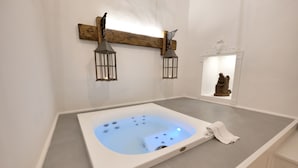 A modern bathroom with a square hot tub, two wall-mounted lanterns, and a statue in a niche. - Dimora San Giuseppe (Lecce)