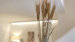 A modern living room with a vase of dried wheat stalks on a glass table, a white sofa, and a minimalist decor style. - Dimora San Giuseppe (Lecce)
