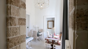 A dining area with a table set for four, surrounded by wicker chairs. A modern pendant light hangs above the table. - Dimora San Giuseppe (Lecce)