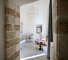 Un comedor con una mesa lista para cuatro personas, rodeada de sillas de mimbre. Una lámpara colgante moderna ilumina la mesa.
