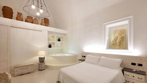 A bedroom with a large bed, a built-in bathtub, and a window with a sculpture. - Dimora San Giuseppe (Lecce)