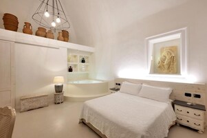 Un dormitorio con una cama grande, una bañera integrada y una ventana con una escultura.