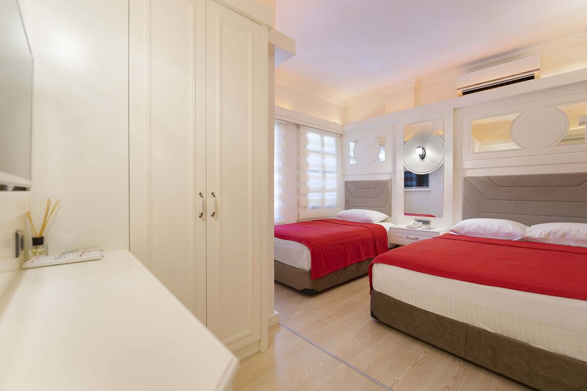 A bedroom with two beds, white walls, and a large wardrobe.