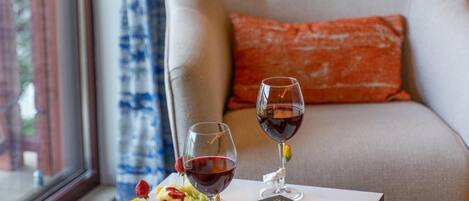 Une pièce chaleureuse avec un fauteuil moelleux, une petite table sur laquelle repose un livre, deux verres à vin et des fruits.