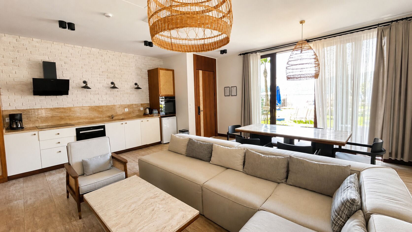 Una cucina moderna con mobili bianchi, forno integrato e zona pranzo con tavolo e sedie.