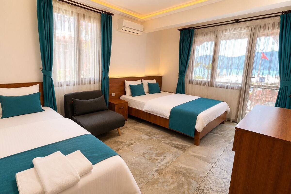Habitación de hotel con dos camas, un escritorio, una silla y vista al mar.