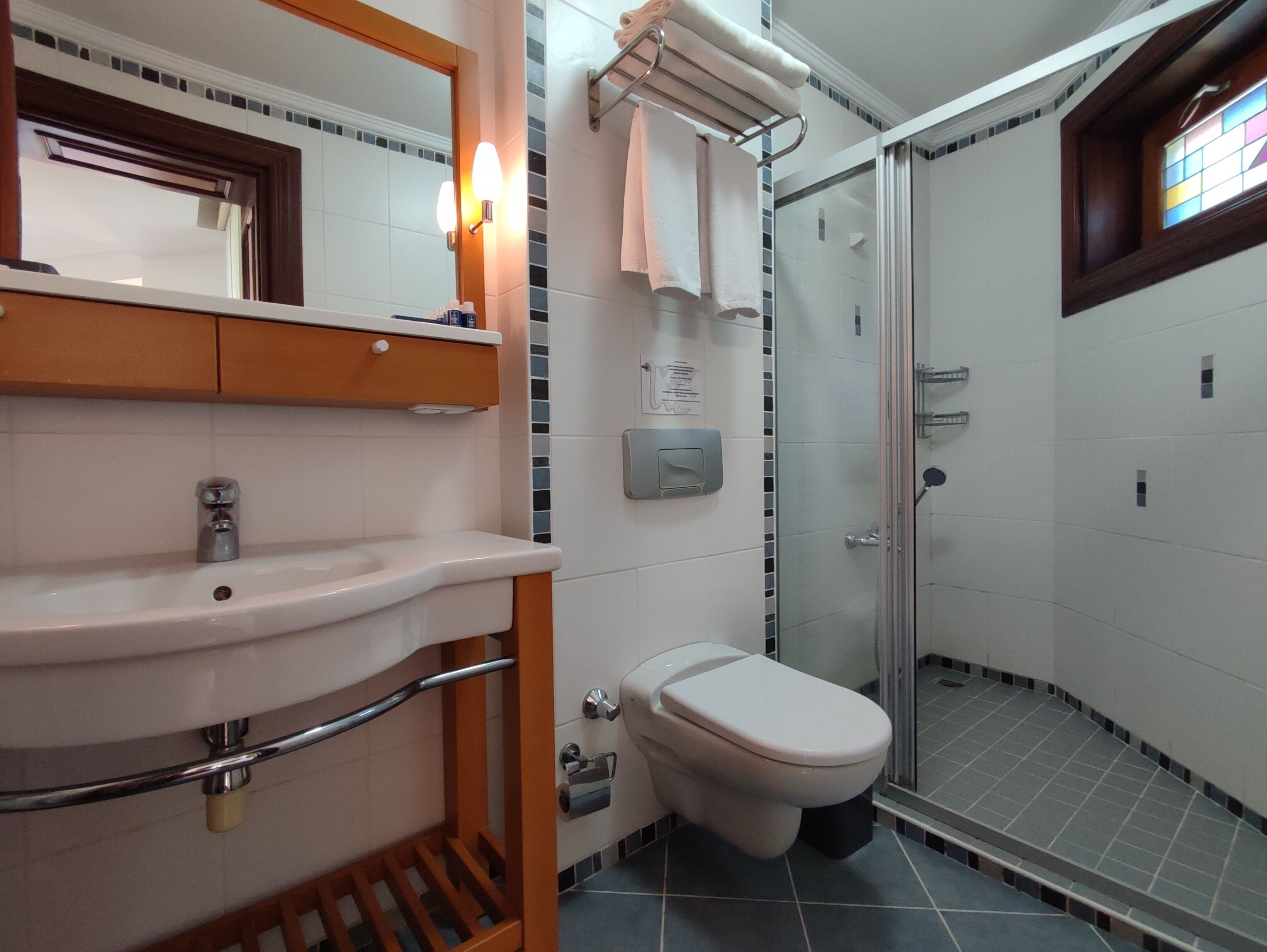 Un bany amb rentamics, mirall, vàter i cabina de dutxa de vidre.