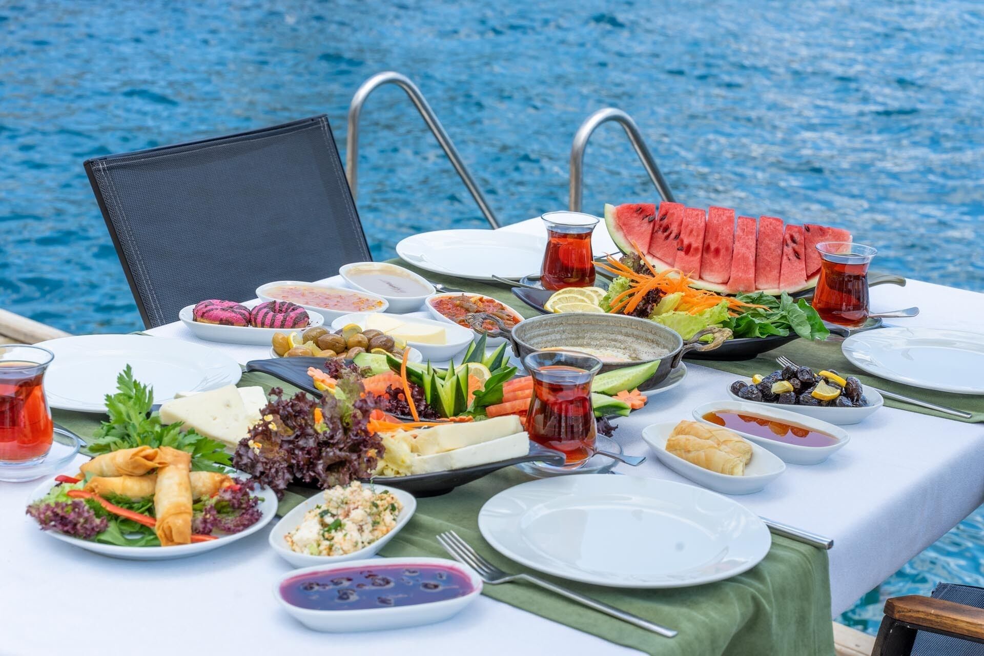 A table set for a meal with various dishes, including watermelon slices, salads, and a teapot.