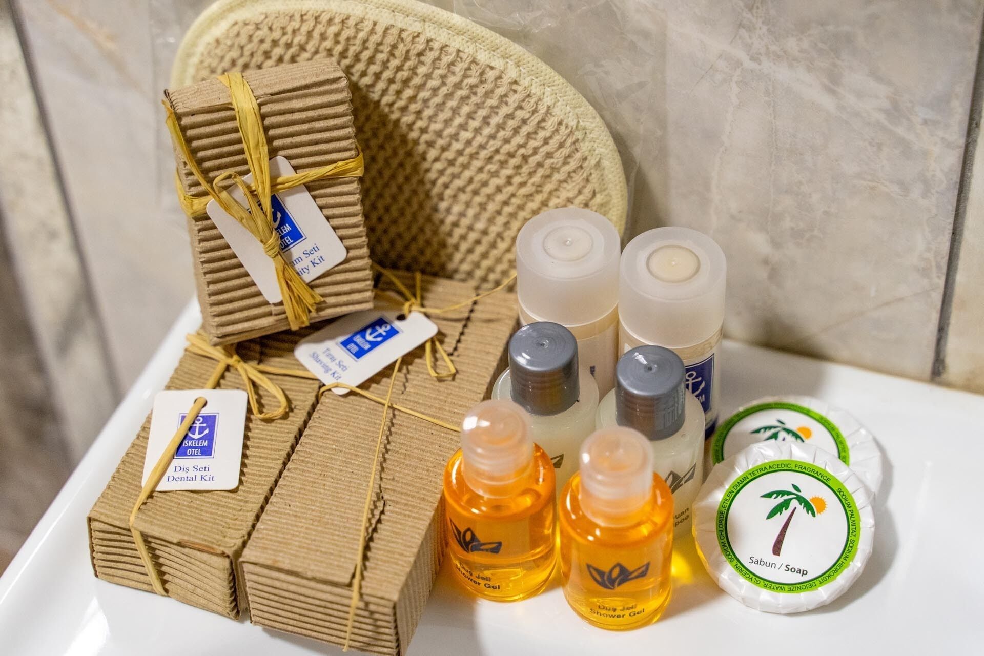 A bathroom with a towel rack, a shower, and toiletries including a dental kit and shower gel.