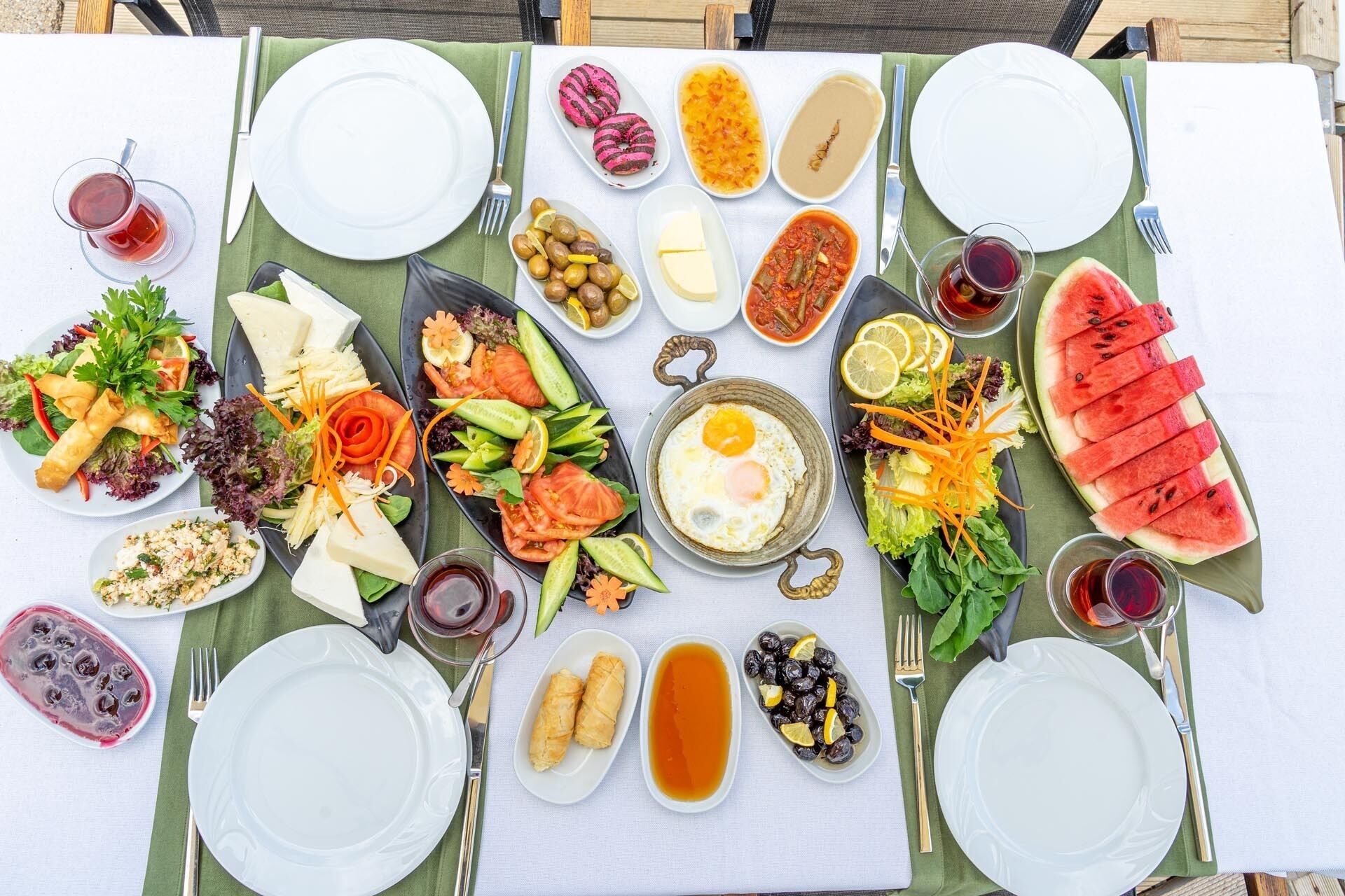 A table set for a meal with various dishes, including salads, eggs, and watermelon.