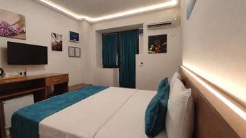 Ein Hotelzimmer mit Bett, Schreibtisch, Fernseher und Klimaanlage.