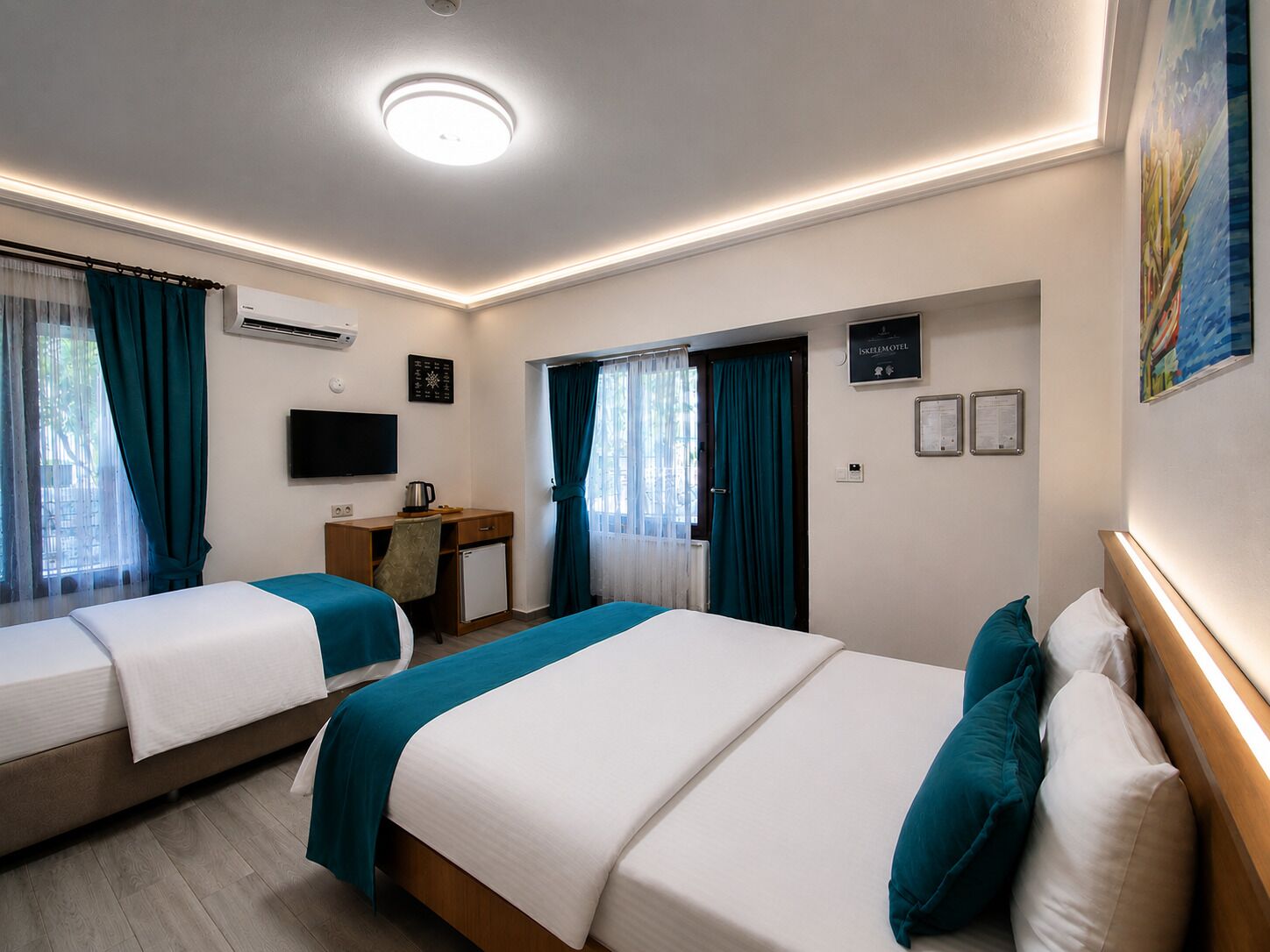A hotel room with two beds, a desk, a chair, a television, and a window with curtains.
