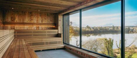 A wooden interior with a large window overlooking a lake.