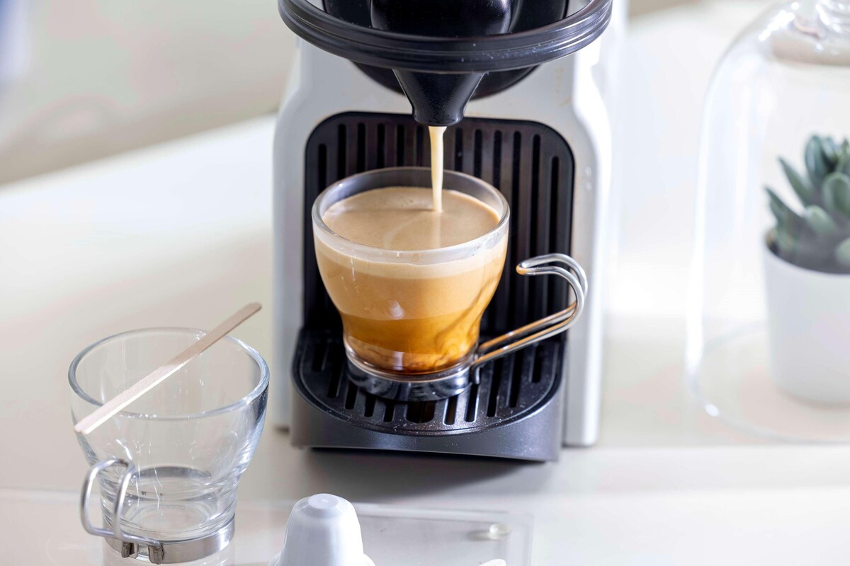 A coffee machine dispensing coffee into a glass cup.