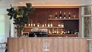 A bar area with a wooden counter, clear chairs, and shelves of bottles. - Best Western Plus Le Roi Arthur Hotel et Spa (Ploërmel)