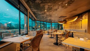 A restaurant with large windows, wicker furniture, and a ceiling mural. - Best Western Plus Le Roi Arthur Hotel et Spa (Ploërmel)