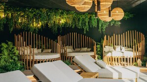 A modern lounge area with wooden dividers, cushioned seating, and hanging greenery. - Best Western Plus Le Roi Arthur Hotel et Spa (Ploërmel)
