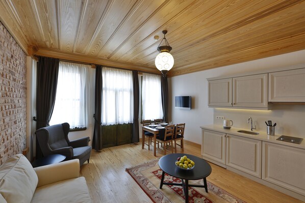 A living room with a sofa, a dining table with chairs, a kitchen area with cabinets, and a wooden ceiling. - Catirga Konak Apartments (Istanbul)
