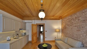 Une cuisine moderne avec des meubles blancs, un plafond en bois et un coin repas comprenant un canapé blanc et une table sur laquelle sont disposées des pommes.