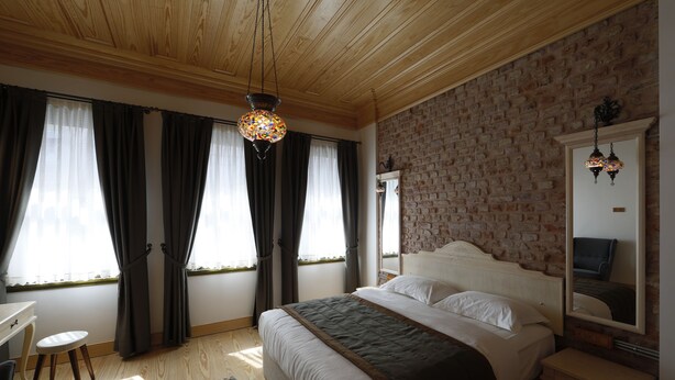 Une chambre avec un grand lit, un plafond en bois, un mur en briques et un miroir.