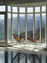Habitación de esquina con amplios ventanales y vistas a la montaña.