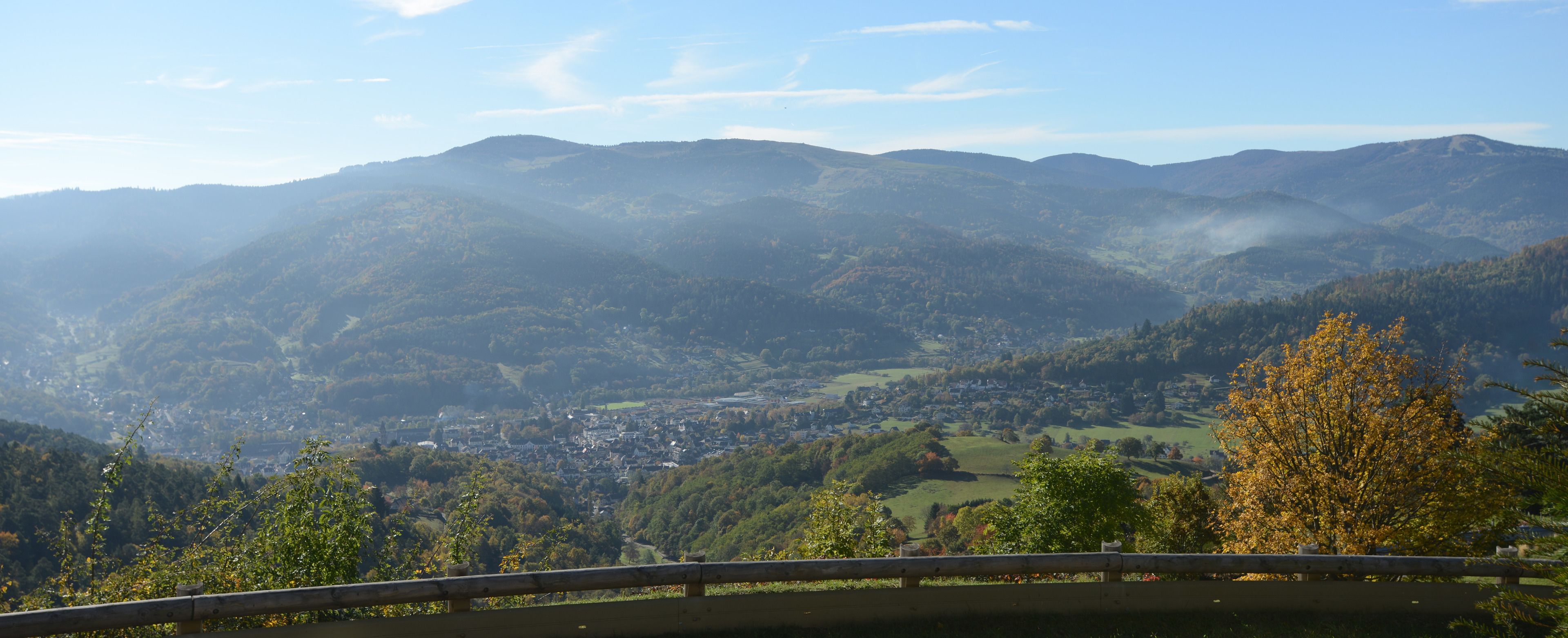 Ein weiter Blick über ein Tal mit einer Stadt, eingebettet zwischen sanften Hügeln und Bergen.