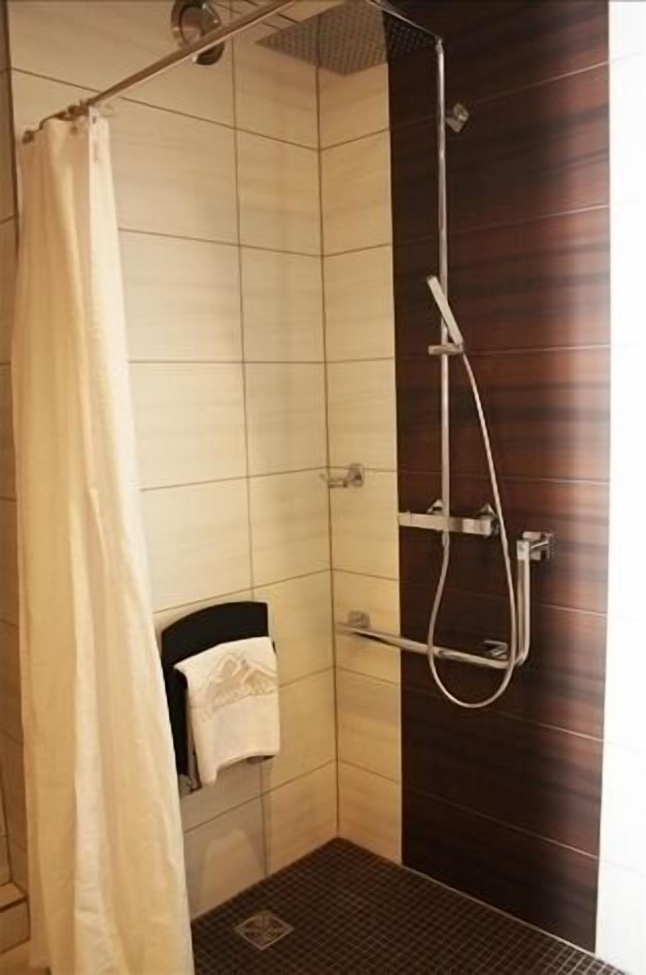 Un espace douche équipé d’un rideau, d’un porte-serviettes et d’un pommeau de douche.