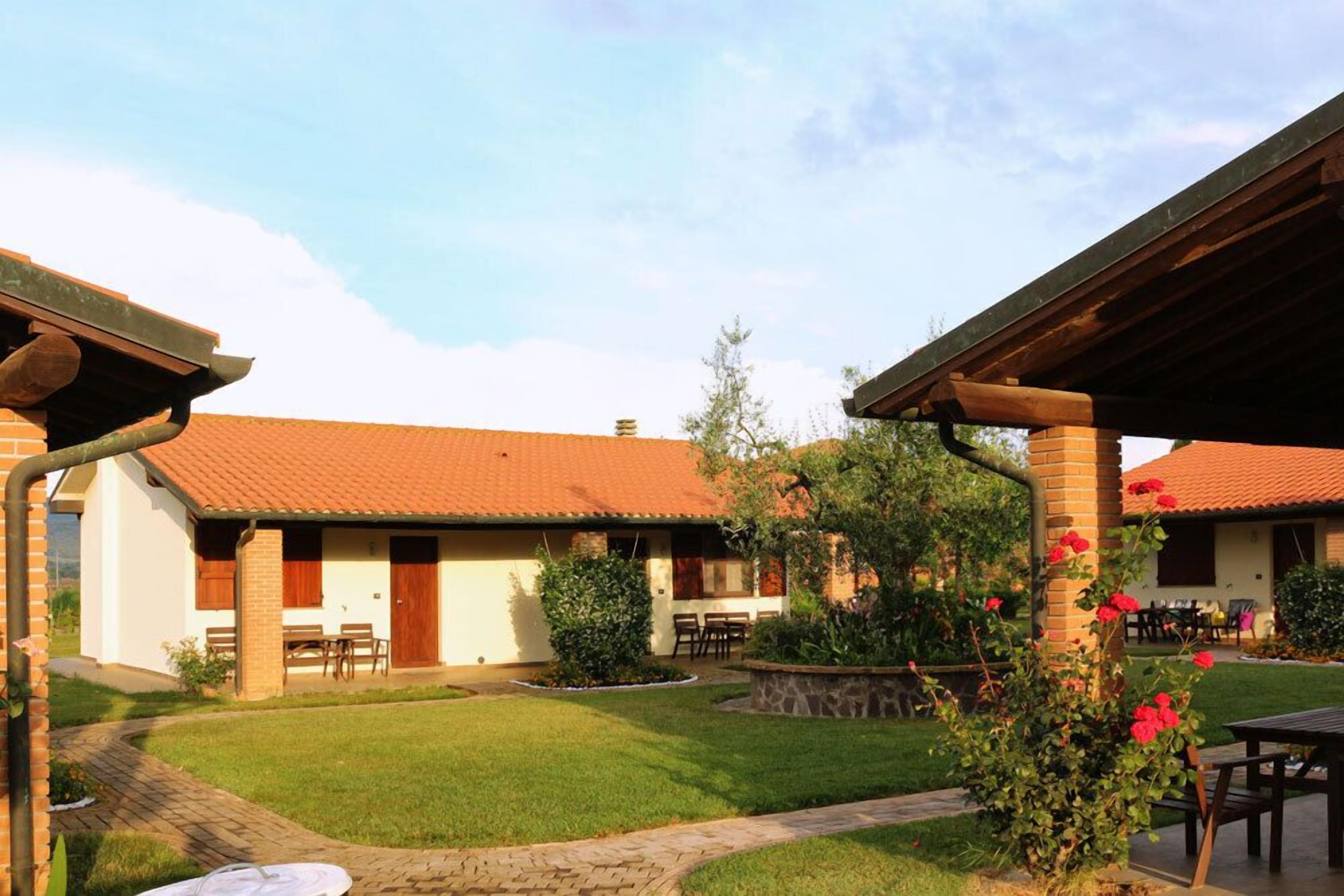 A courtyard with a brick building, a covered patio, and a well-maintained lawn.