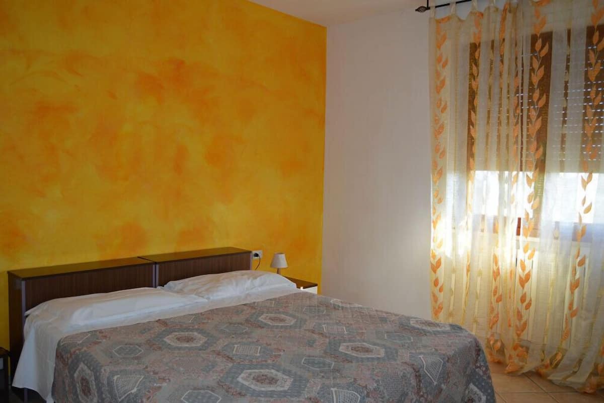 Una habitación de hotel con una cama, una mesita de noche y una lámpara.