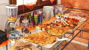 A buffet with various food items and beverages, including pastries, bread, and a variety of condiments.