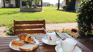 A table with a croissant, a slice of bread, and a cup of coffee.