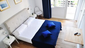 A neatly made bed with white and blue bedding, a bedside table with a lamp, and a small plant. - Hostal Porto Mar (Salou)