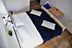 A bedroom with a large bed, a bedside table, a chair, and a small table. - Hostal Porto Mar (Salou)