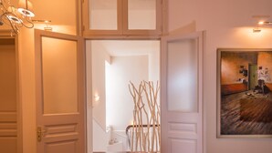 A hallway with open doors leading to a staircase and a room with a painting. - Palladian Home (Athens)