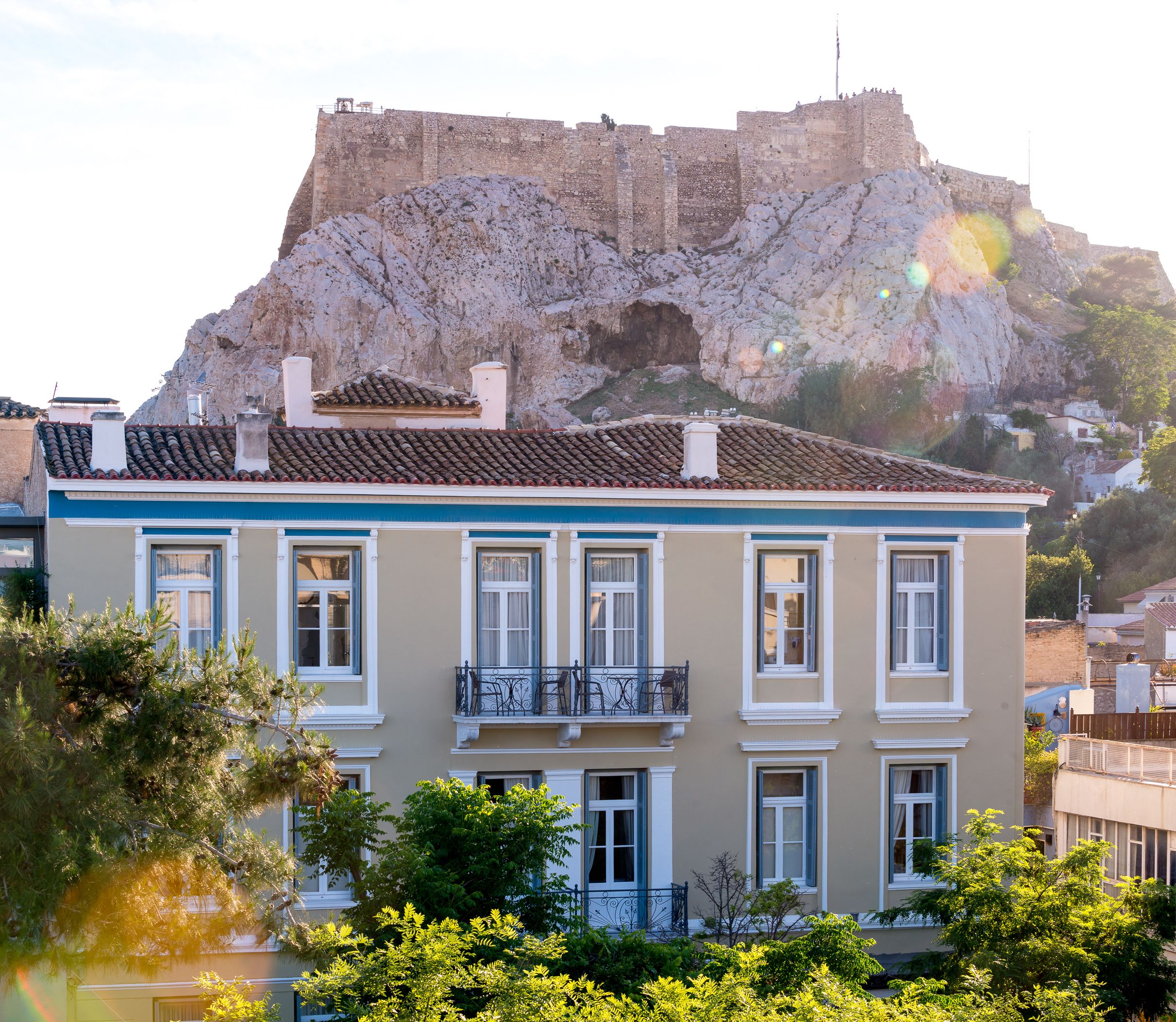 Un bâtiment doté d’un balcon, offrant une vue sur un fort historique, et avec une végétation luxuriante au premier plan.