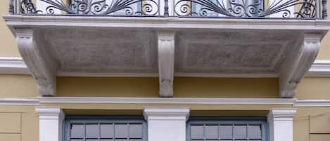A two-story building with a balcony featuring ornate wrought iron railings, large double doors with decorative panels, and a plaque reading "Palladian Home".