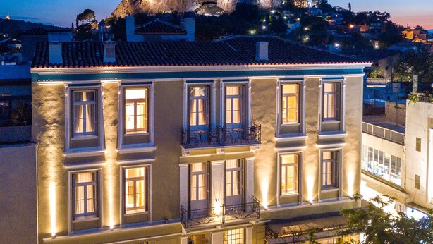A building with multiple balconies and a prominent rock formation in the background. - Palladian Home (Athens)