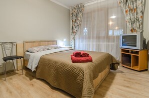 A bedroom with a bed, a chair, a TV, and curtains. - Rent Kiev Vladimirskaya (Kyiv)