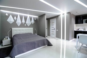 A modern bedroom with a large bed, bedside tables, a desk, and a chair. - Rent Kiev Vladimirskaya (Kyiv)