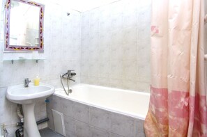 A bathroom with a white sink, a mirror with a decorative frame, a bathtub, and a shower curtain. - Rent Kiev Vladimirskaya (Kyiv)