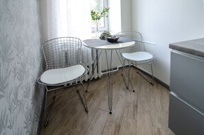 A small dining area with two wire-frame chairs, a round table, and a vase with flowers. - Rent Kiev Maidan Nezalezhnosti (Kyiv)