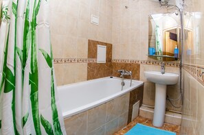 Bathroom features a large bathtub, sink, and shower, along with a towel rack.