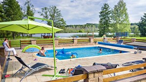 A swimming pool with inflatable toys, a green umbrella, and a wooden deck with benches. - Rezydencja nad jeziorem - Pestkownica (Krzyz Wielkopolski)