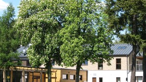 A building with a modern architectural style, featuring a mix of brick and wood elements, and surrounded by lush greenery and trees. - Rezydencja nad jeziorem - Pestkownica (Krzyz Wielkopolski)