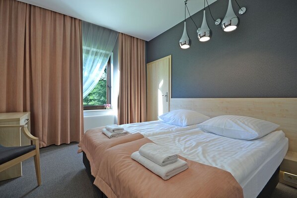 Ein Hotelzimmer mit einem großen Bett, zwei Kissen, einem Nachttisch und einem Sessel.
