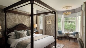 A four-poster bed with a wooden frame, a matching nightstand, a chair, and a table with a lamp. - Marcliffe (Aberdeen)