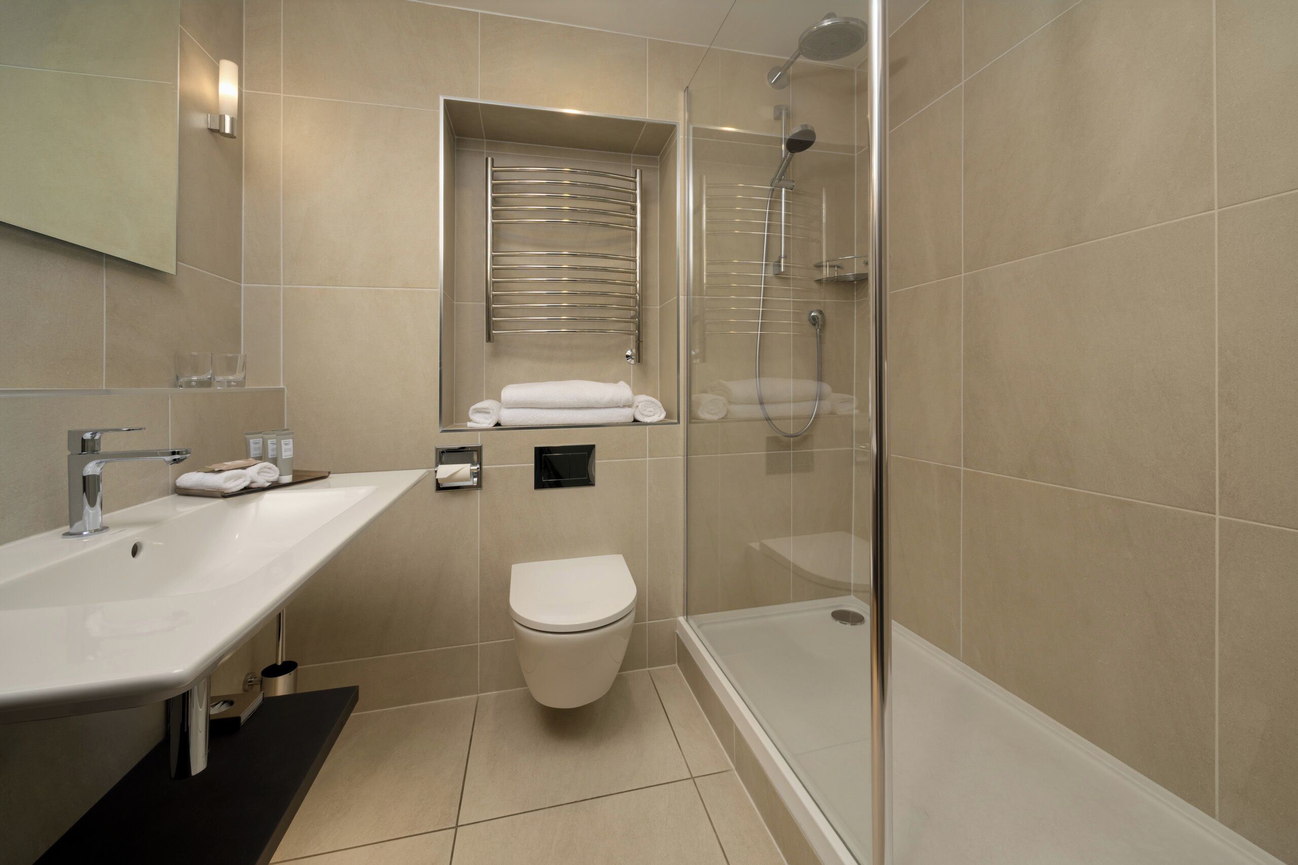 A modern bathroom with a glass-enclosed shower, a white sink, and a toilet.