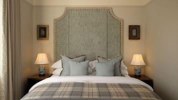 A neatly made bed with a plaid bedspread, two bedside lamps, and a headboard with a decorative trim.