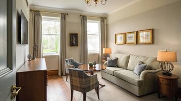 Un salon comprenant un canapé, des fauteuils, une table basse, une lampe et un téléviseur.